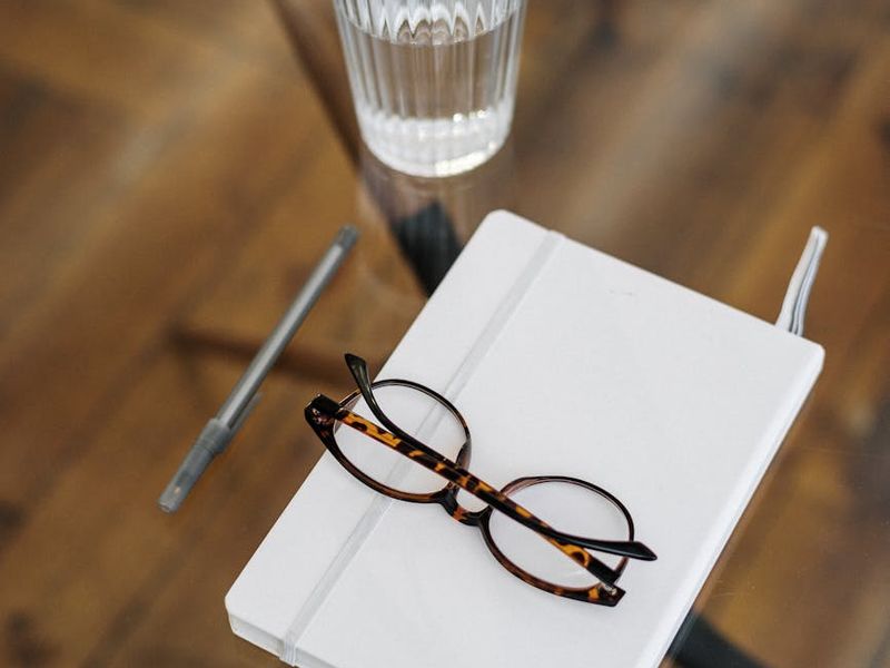 Elegant glass of water and notebook on a wooden desk